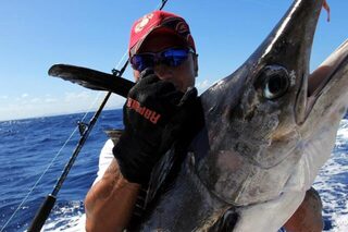 Крупная морская рыба с вытянутым рылом в руках мужчины