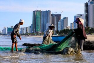На пляже Дананга разбираем рыболовную сеть у кромки воды