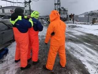 Трое в оранжевом у заснеженной гавани