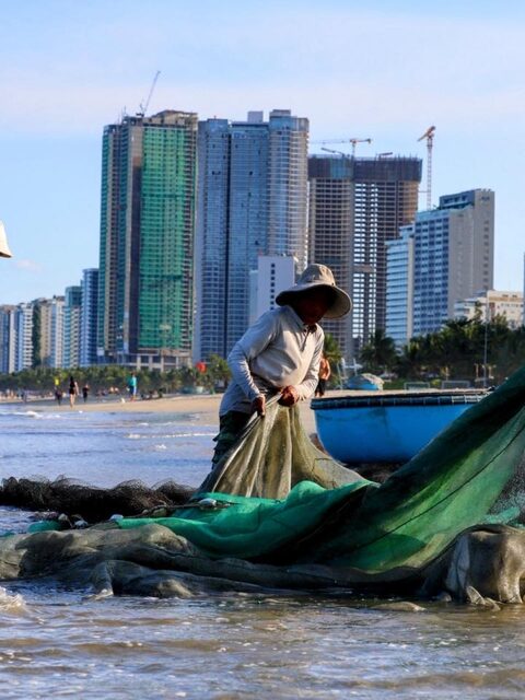 На пляже Дананга разбираем рыболовную сеть у кромки воды