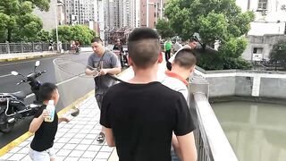 Рыбалка в центре Shanghai городские набережные парки и удивлённые прохожие вокруг рыбака
