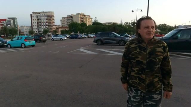 Альфредо вываживает рыбу на болонскую удочку в туристическом порту Ольбии