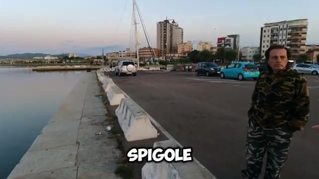 Альфредо вываживает рыбу на болонскую удочку в туристическом порту Ольбии